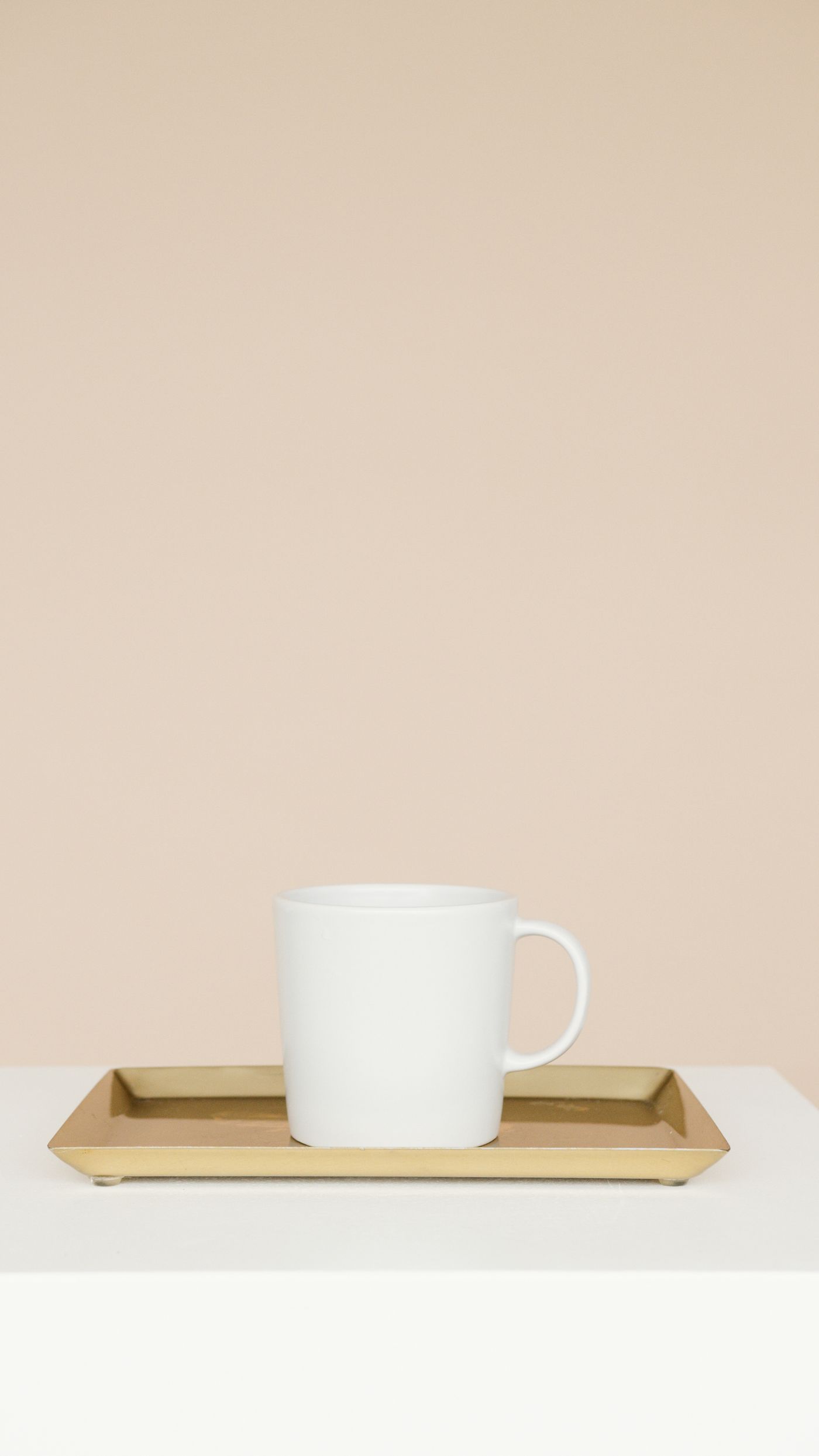 A cup served on a warm brass serving tray against a soft neutral background