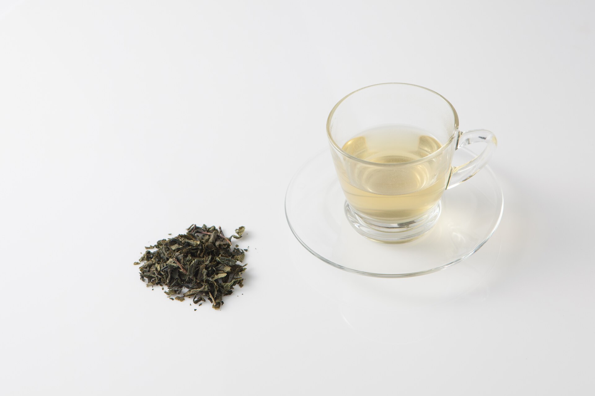 A cup of Korean green tea beside loose tea leaves